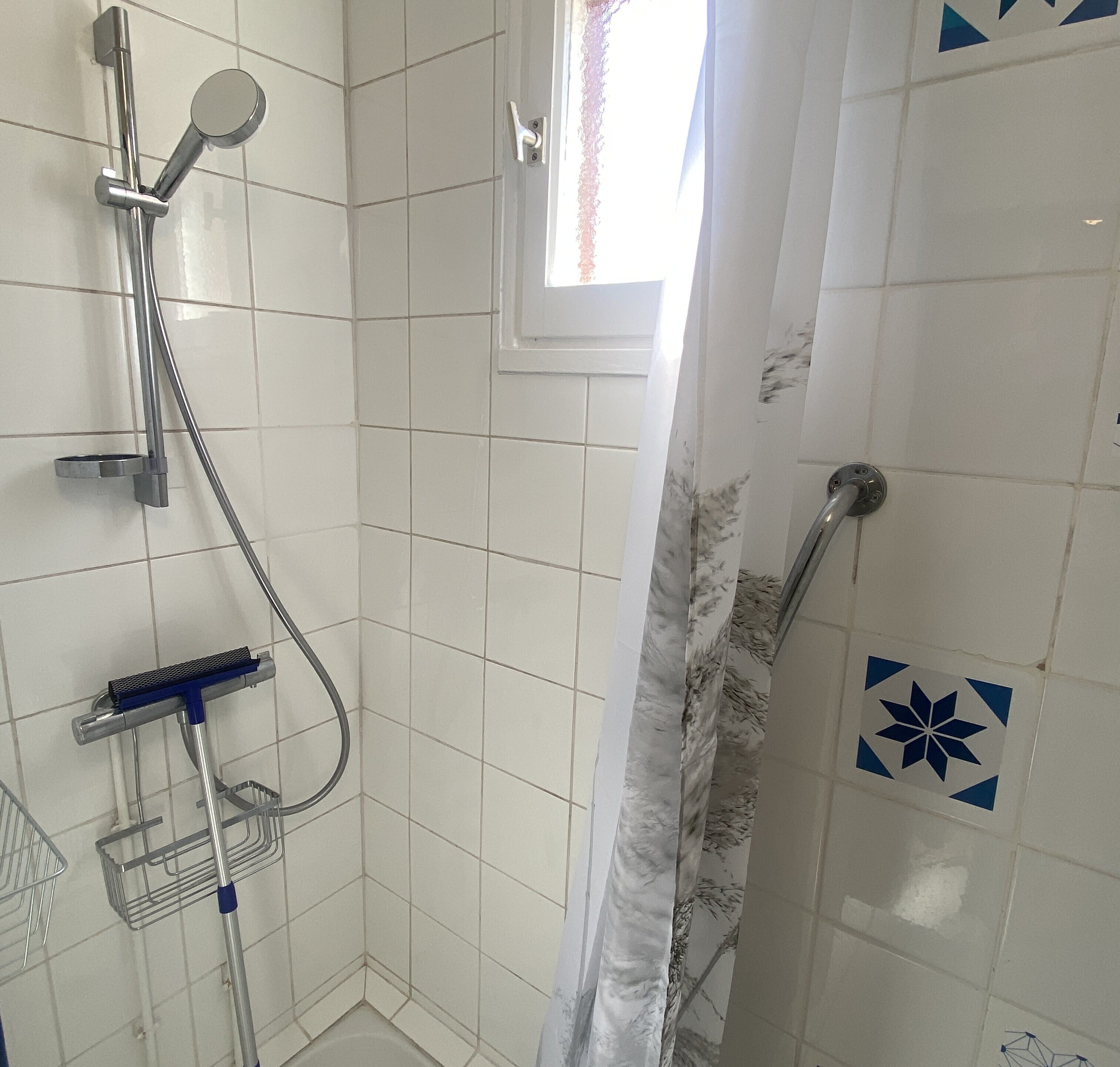 Un espace douche équipé d’un pommeau de douche à main, d’un robinet mural et d’une étagère de douche.