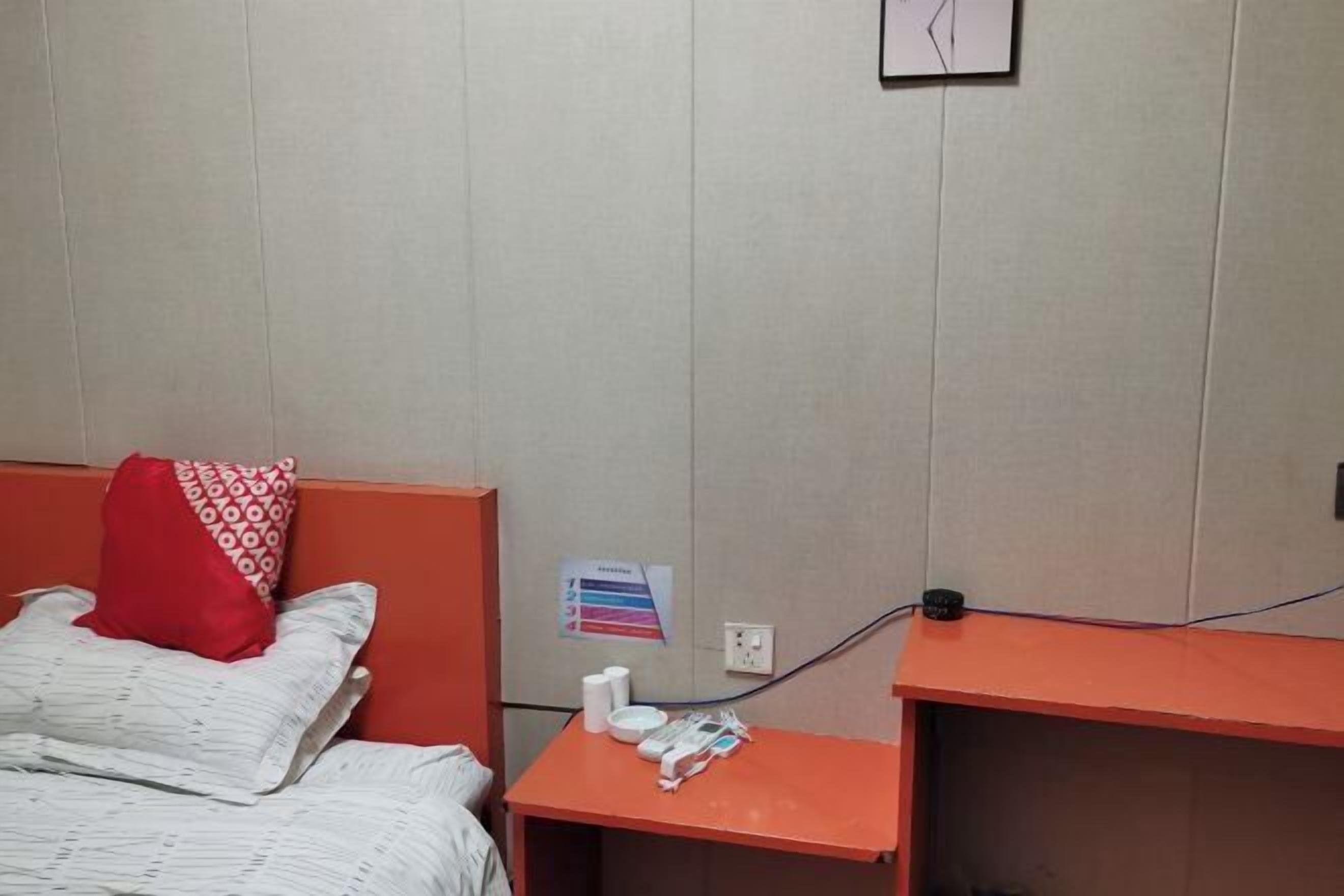 A hotel room with a bed, a nightstand, and a small table with a power outlet and some items on it.