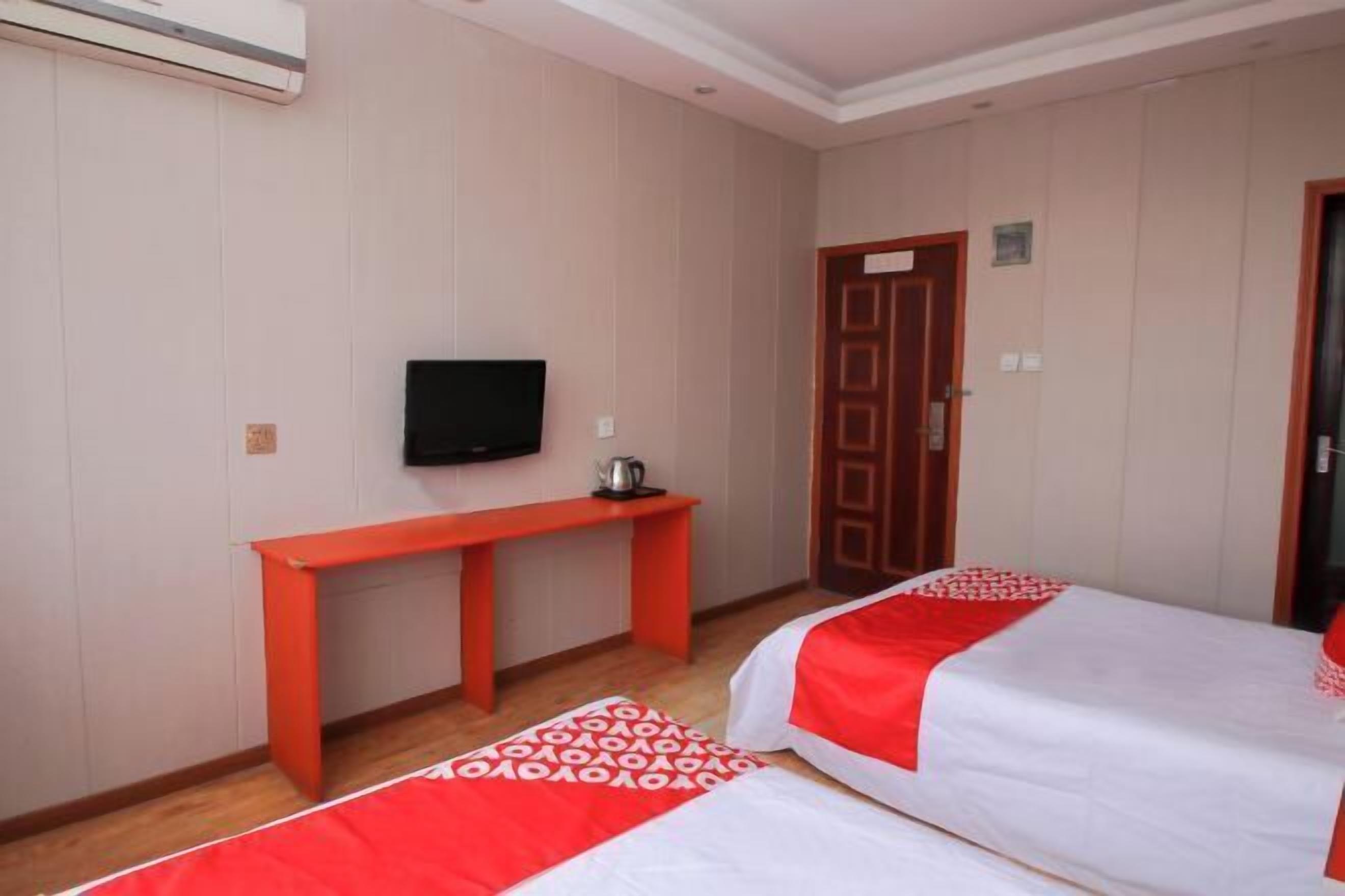 A hotel room with two beds, a TV, a desk, and a door.