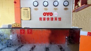 Un comptoir d’accueil avec des horloges, un tableau affichant le menu et une enseigne indiquant « OYO ».