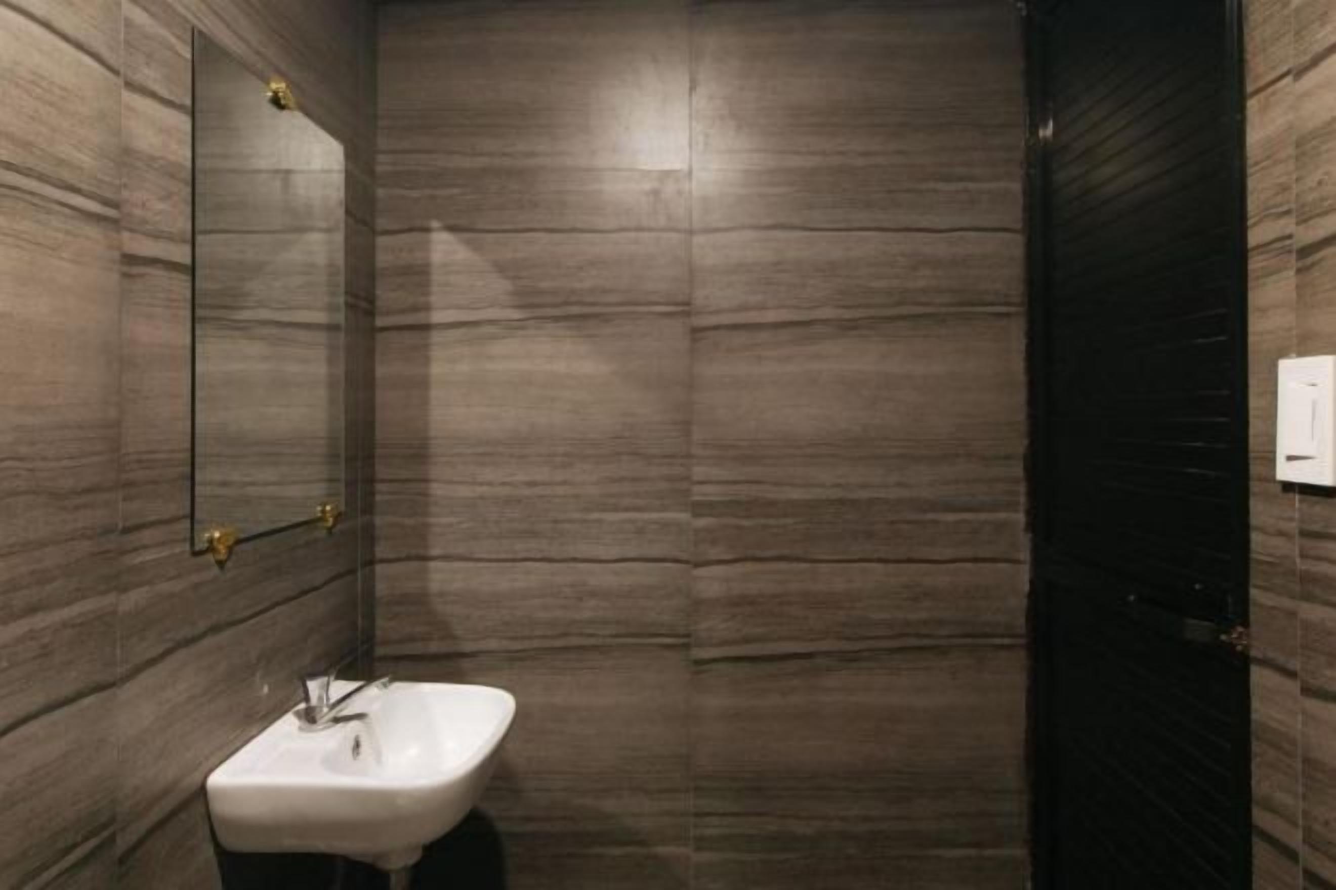 A bathroom with a marble wall, a sink, and a mirror.