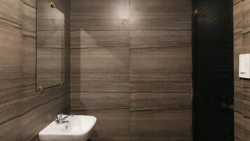A bathroom with a marble wall, a sink, and a mirror.
