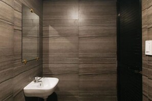 A bathroom with a marble wall, a sink, and a mirror. - Alamaris Resort RedPartner (Morong)