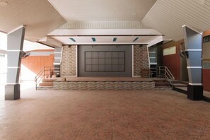 A spacious lobby with a central seating area, a staircase, and a large wall with a screen.