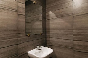 A bathroom with a white sink, a mirror, and a wall with a wood-like texture. - Alamaris Resort RedPartner (Morong)