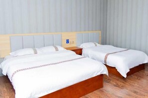 A hotel room with two single beds, wooden headboards, and a light-colored wall. - Fuyuan Xinyuan Hotel (Fuyuan)