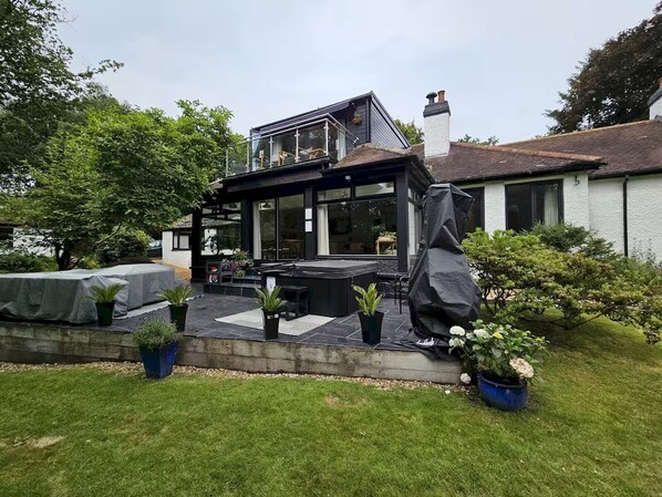 A modern house with a patio, outdoor seating, and potted plants.