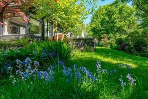 A lush garden with a stone fountain, a gazebo, and a variety of flowering plants.