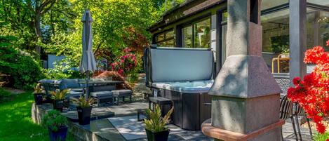 A patio with outdoor furniture, a hot tub, and a stone oven.