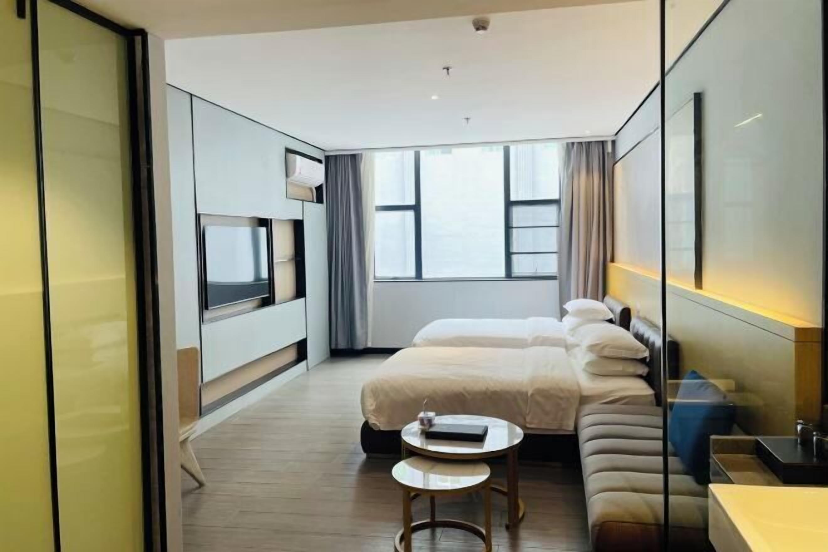 A modern hotel room with a large bed, a small round table, a TV, and a bathroom area.
