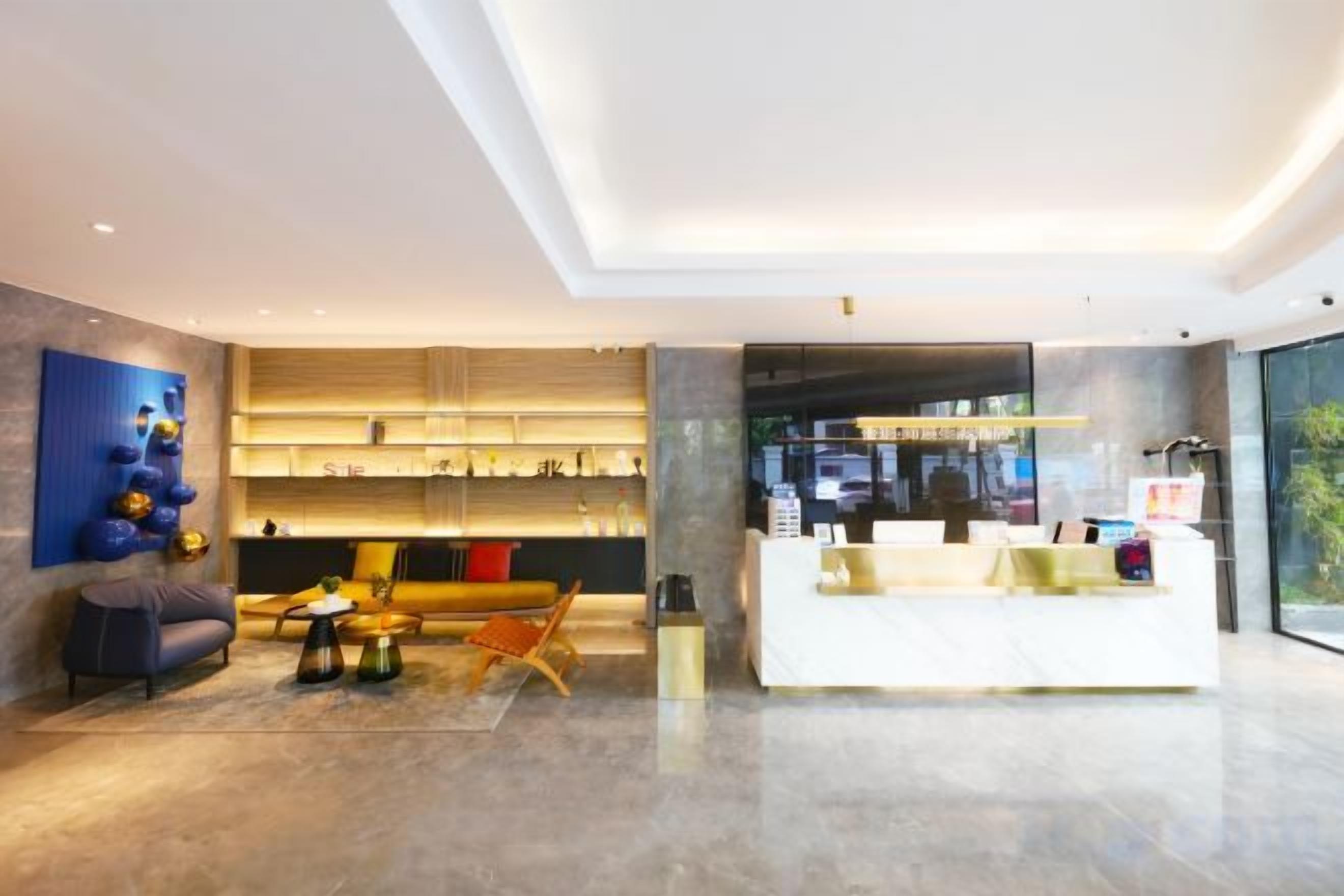 A modern hotel lobby with a reception desk, seating area, and a large window.