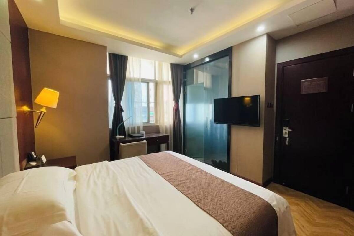 Una habitación de hotel con cama, escritorio, silla, televisor y puerta.