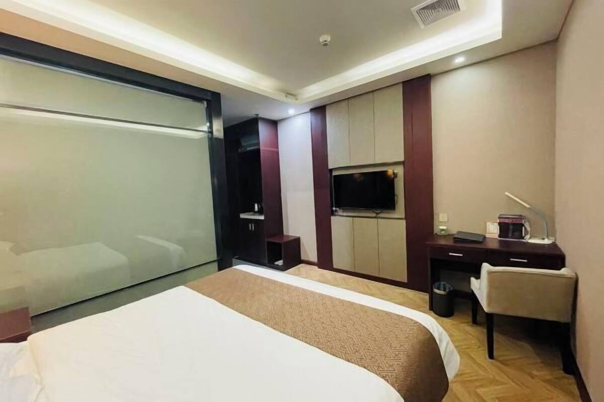 Una habitación de hotel con cama, escritorio, silla, televisor y armario.