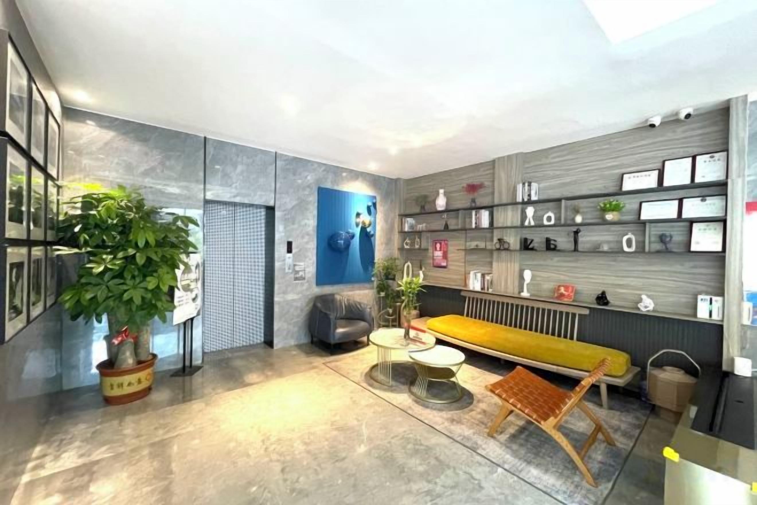 A modern interior with a sofa, a coffee table, a potted plant, and a wall-mounted shelf with various items.