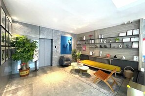 Un interior modern amb un sofà, una taula de café, una planta en test i una prestatgeria de paret amb diversos objectes.
