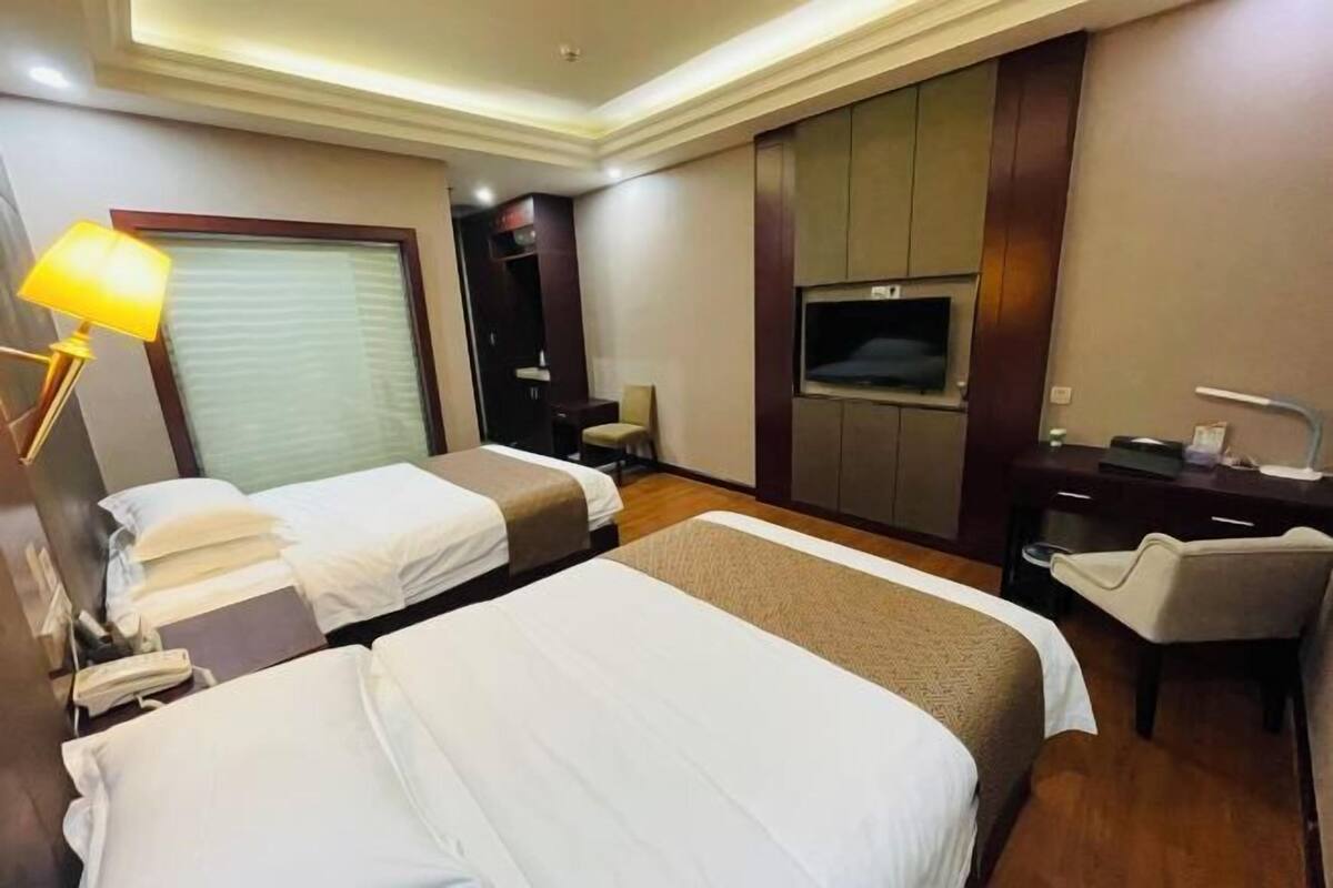 Habitación de hotel con dos camas, televisión, escritorio y una silla.