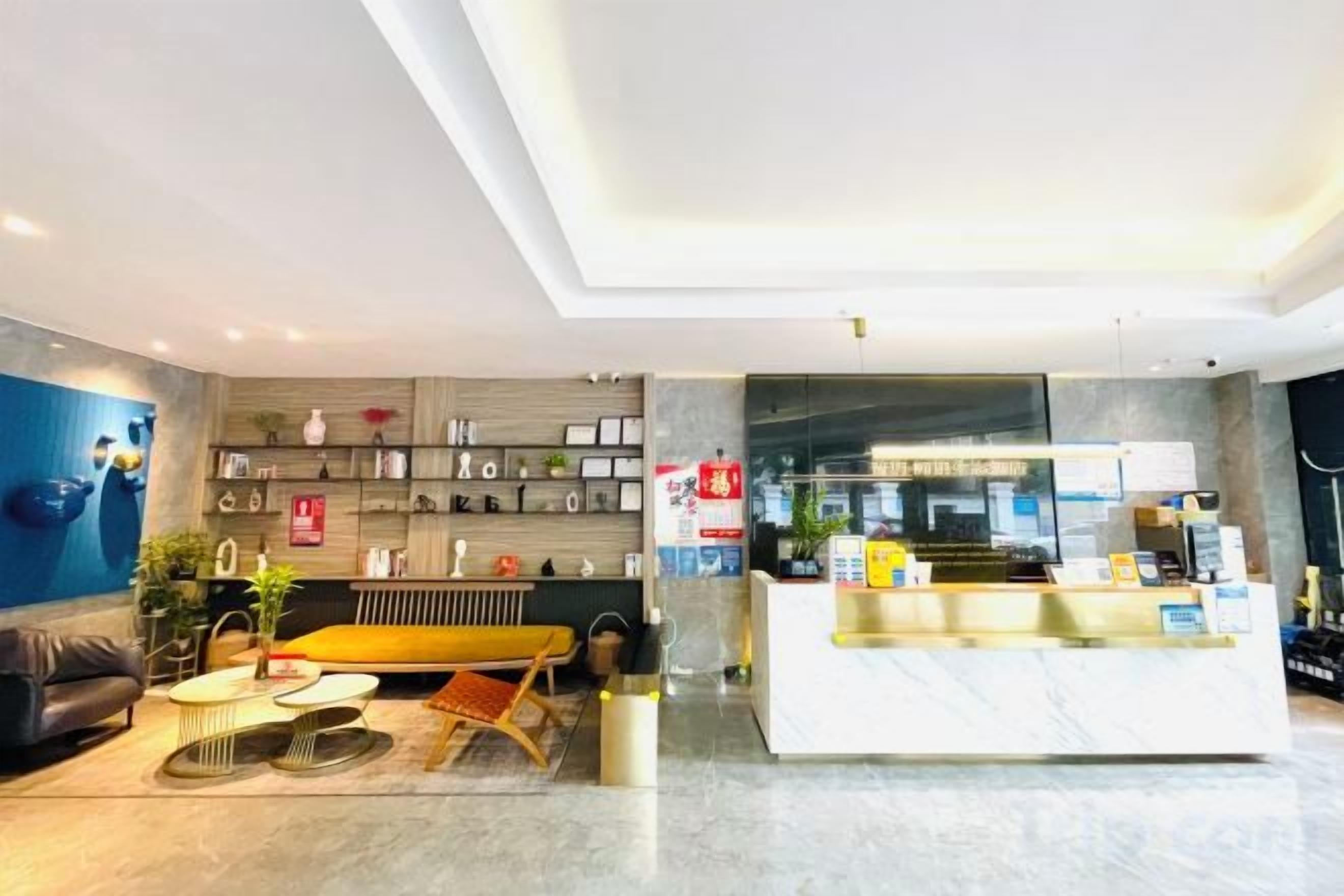 A modern hotel lobby with a reception desk, seating area, and a wall with decorative items.