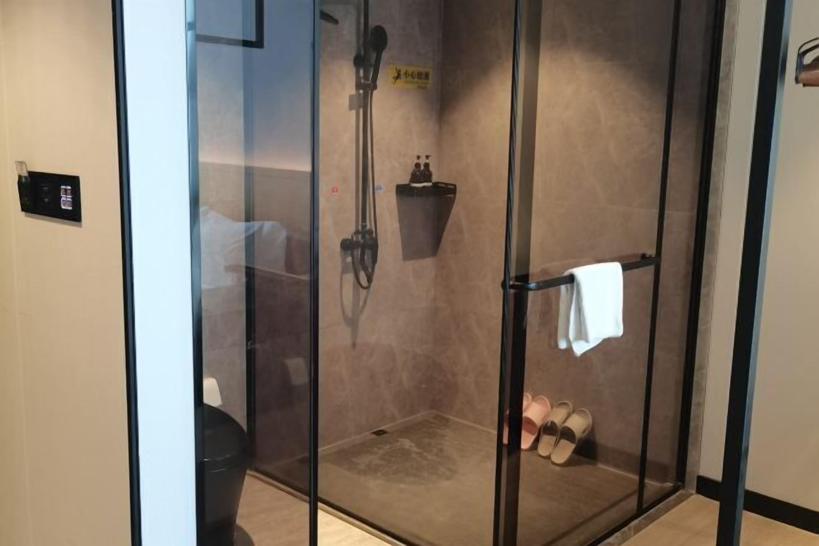 A glass-enclosed shower area with a towel rack and a small shelf.