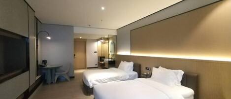Une chambre d’hôtel avec deux lits, une petite table, une télévision et un miroir.