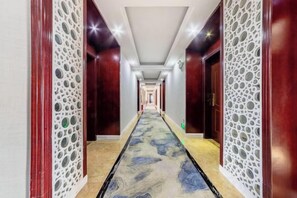 Un pasillo de hotel con alfombra estampada, puertas de madera y paneles decorativos.