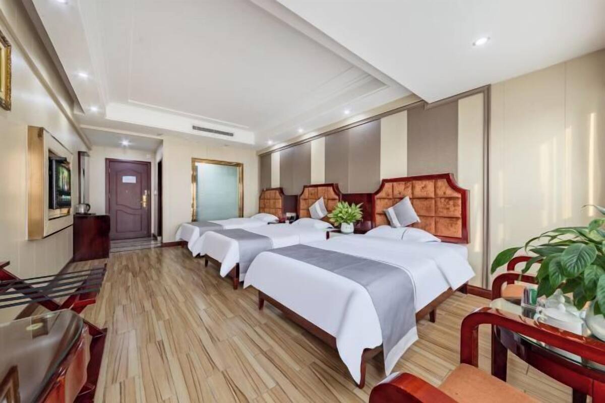 Habitación de hotel con tres camas, un escritorio y una silla.