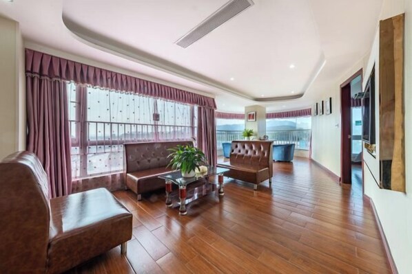 A spacious living room with a large window, a sofa, a coffee table, and a TV. - Fuzhicheng Boutique Hotel (Yuantan Railway Station Branch) (Qingyuan)