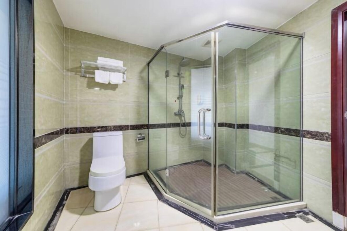 A glass-enclosed shower stall with a toilet and a towel rack.