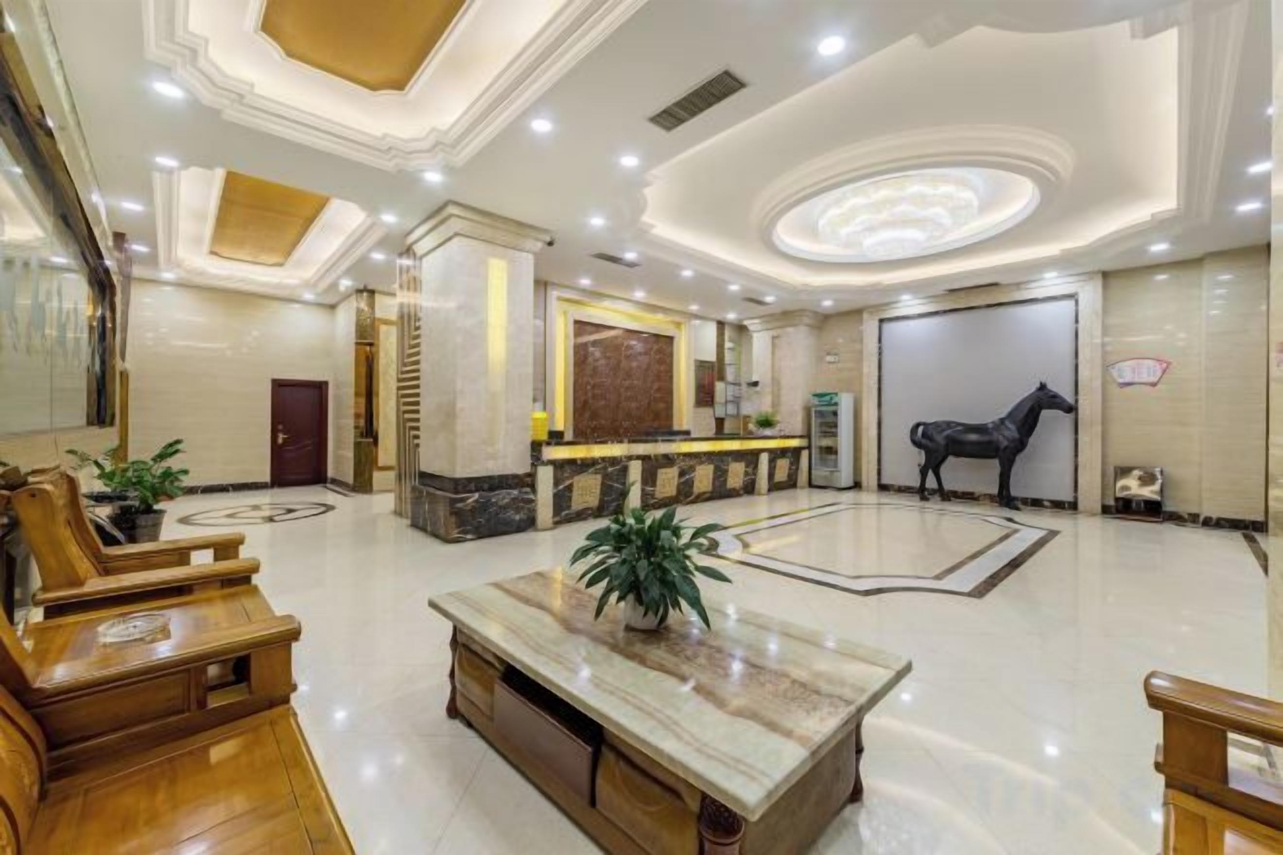 A spacious lobby with a reception desk, seating area, and a decorative horse statue.