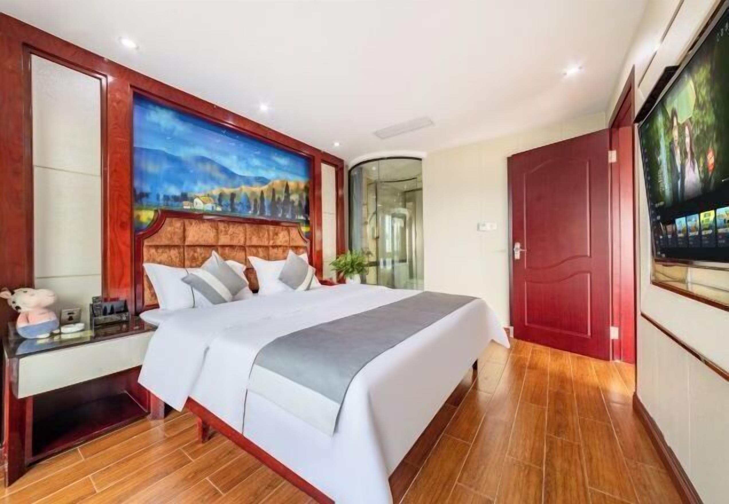Habitación de hotel con una cama grande, un escritorio con silla, un cuadro en la pared y un televisor.