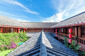 A traditional courtyard with tiled roofs and wooden structures. - Mu Shi Yuan Inn (Lijiang)