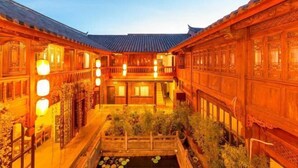 A traditional courtyard with wooden buildings, a central water feature, and lanterns. - Mu Shi Yuan Inn (Lijiang)
