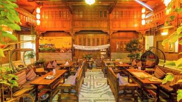 Uma hospedaria tradicional com interiores de madeira, várias áreas de estar e um tapete decorativo central.