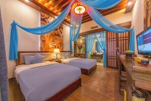Quarto de hotel com duas camas, uma escrivaninha, uma TV e uma luminária decorativa no teto.