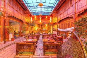 An interior with traditional wooden furniture, a central aisle, and a glass ceiling. - Mu Shi Yuan Inn (Lijiang)
