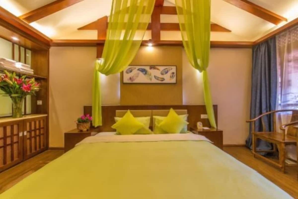A hotel room with a bed, a nightstand, a chair, and a window with curtains.