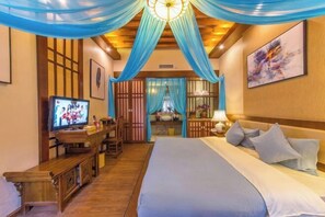 Quarto de hotel com cama, televisão, escrivaninha e banheiro visível por uma porta.
