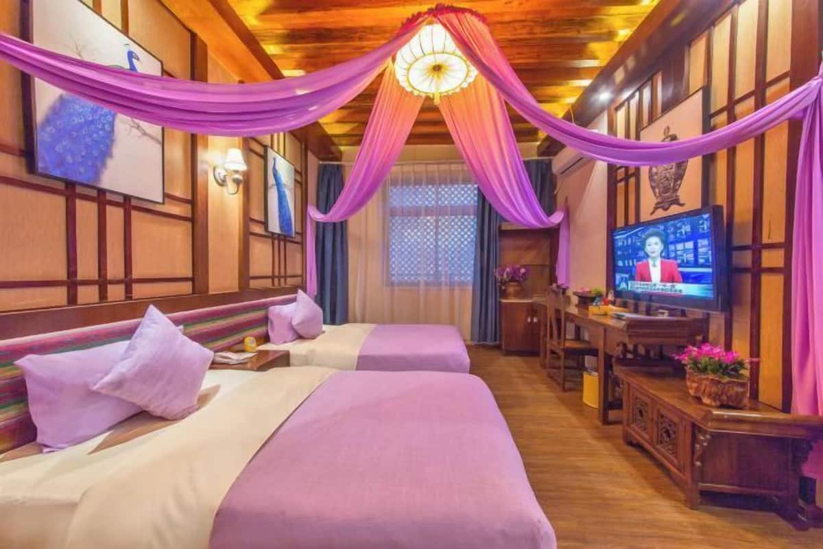A hotel room with two beds, a television, wooden furniture, and a decorative ceiling.