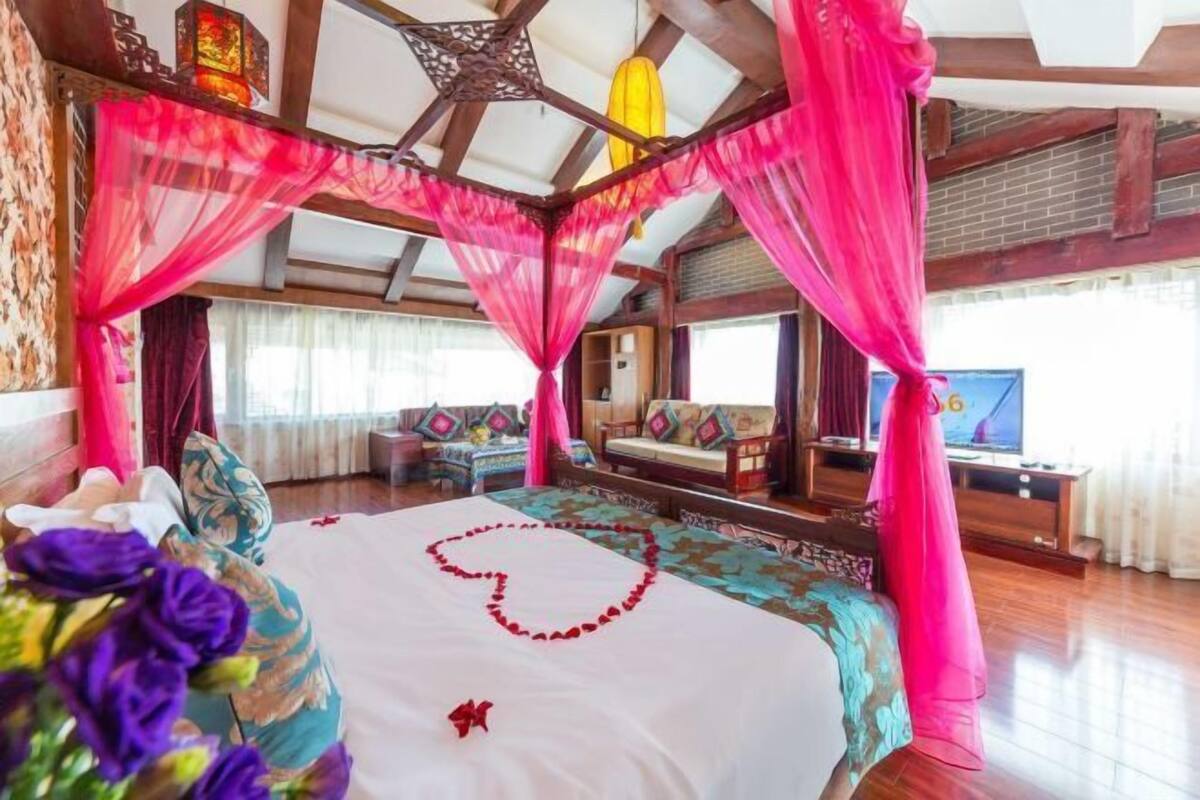 A room with a bed, a TV, and a wooden ceiling structure.