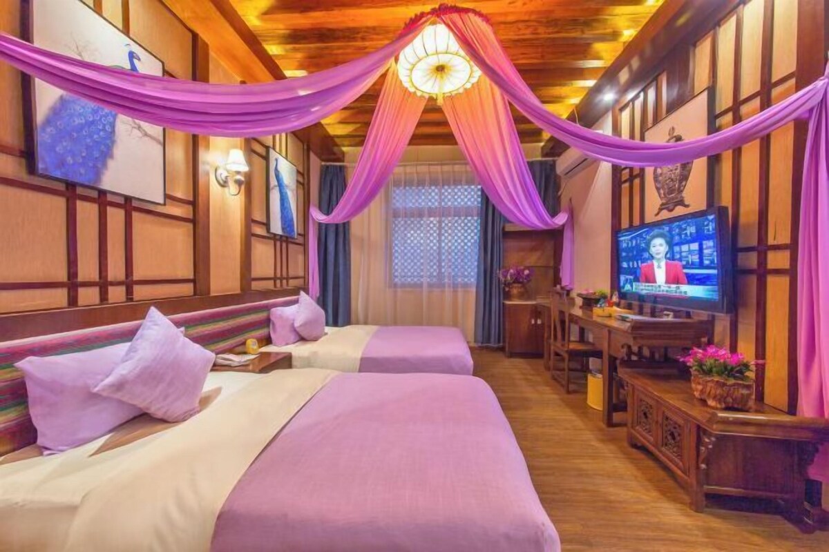 Quarto de hotel com duas camas, televisão e teto de madeira.