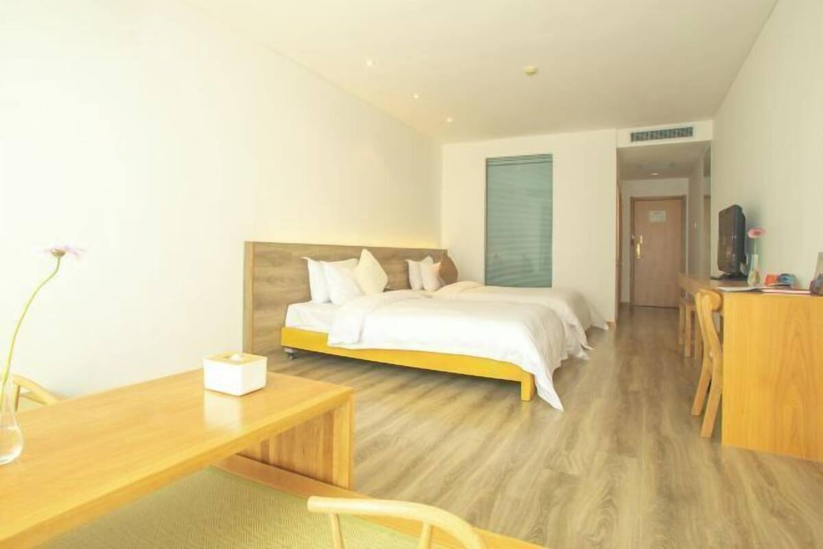 A hotel room with a bed, bedside table, and a desk with a chair.