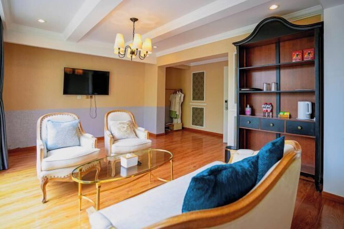 A living room with two armchairs, a sofa, a glass coffee table, a television, and a bookshelf.