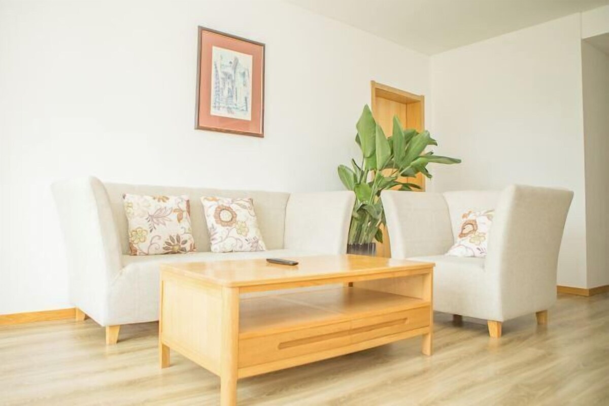 Ein Wohnzimmer mit einer Couch, einem Couchtisch und einer Topfpflanze.