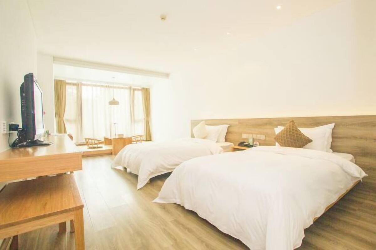 A hotel room with two beds, a desk, and a television.