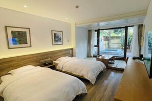A hotel room with two beds, a wooden headboard, a large window with a view, and a flat-screen TV.