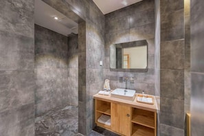 A modern bathroom with a large mirror, a wooden vanity, and a marble wall.
