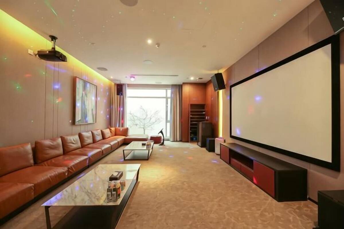 A modern living room with a large screen, leather sofa, and a coffee table.