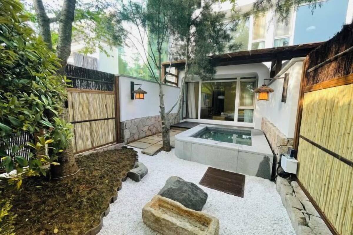 A modern outdoor area with a hot tub, stone walls, and a bamboo fence.