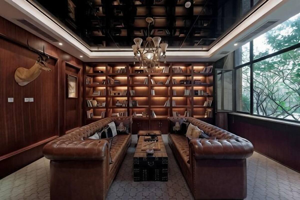 A library with bookshelves, leather sofas, and a chandelier.