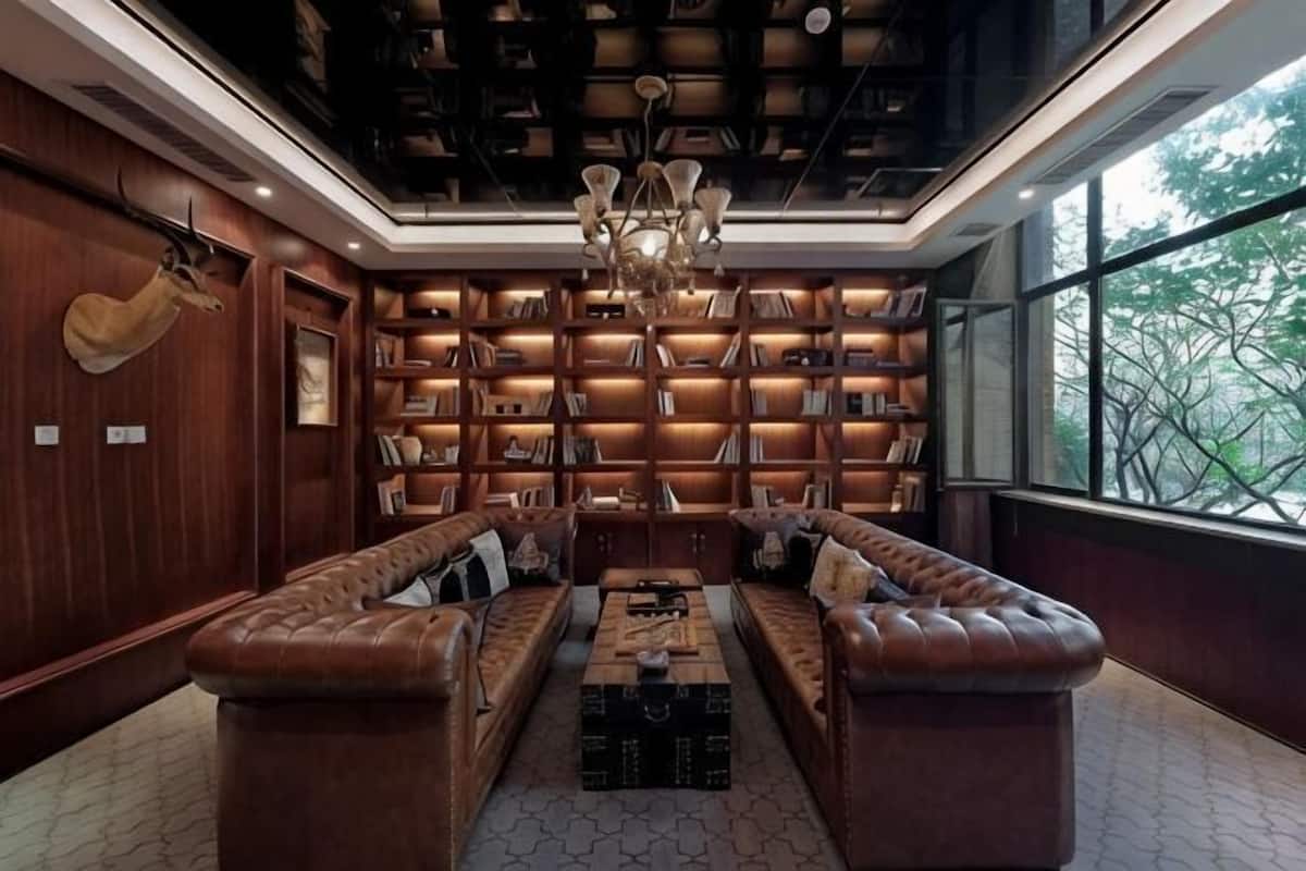 A library with bookshelves, leather sofas, and a chandelier.