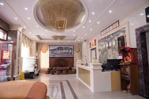 A hotel lobby with a reception desk, a large chandelier, a seating area with a sofa, and a wall-mounted television. - Huizhou Qibin Homestay (Huidong)